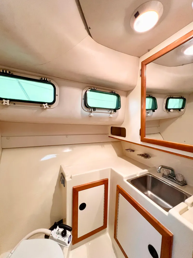 Slide: The Image of Interior of 2000 Albin 28 Tournament Express boat, featuring a compact bathroom with sink and storage. - 15