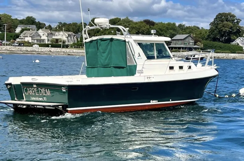 Slide: The Image of 2000 Albin 28 Tournament Express boat on water, green and white, named "Carpe Diem". - 2