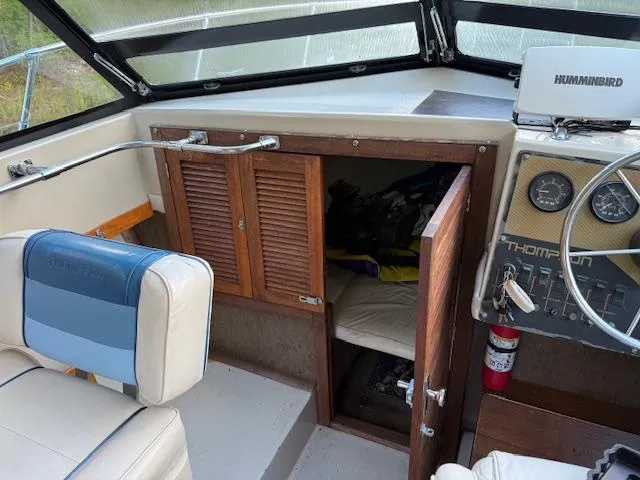 Slide: The Image of 1990 Thompson 240 Fisherman boat interior with steering wheel, gauges, and storage cabinet. - 11