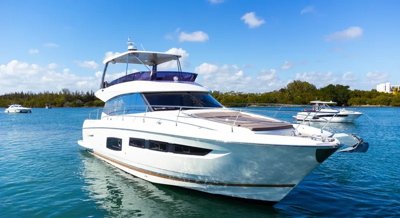 The Image of 2018 Prestige 560 Flybridge yacht cruising on a sunny day in clear blue waters. - 0
