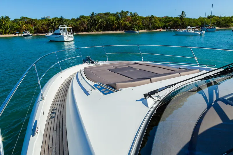Slide: The Image of 2018 Prestige 560 Flybridge yacht on serene blue water near lush shoreline. - 14