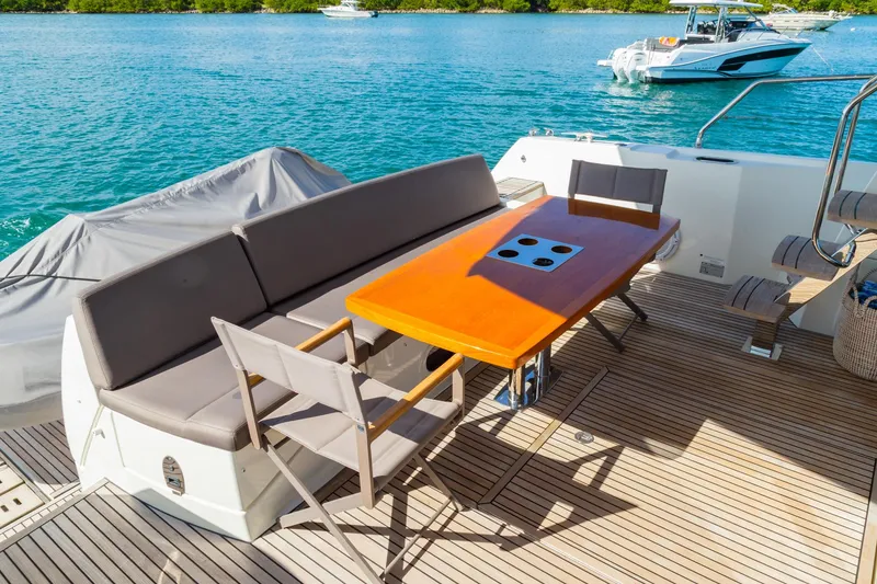 Slide: The Image of Prestige 560 Flybridge 2018 yacht deck with seating and table, overlooking serene blue waters. - 16