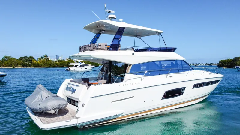 Slide: The Image of 2018 Prestige 560 Flybridge yacht cruising on clear blue water. - 2