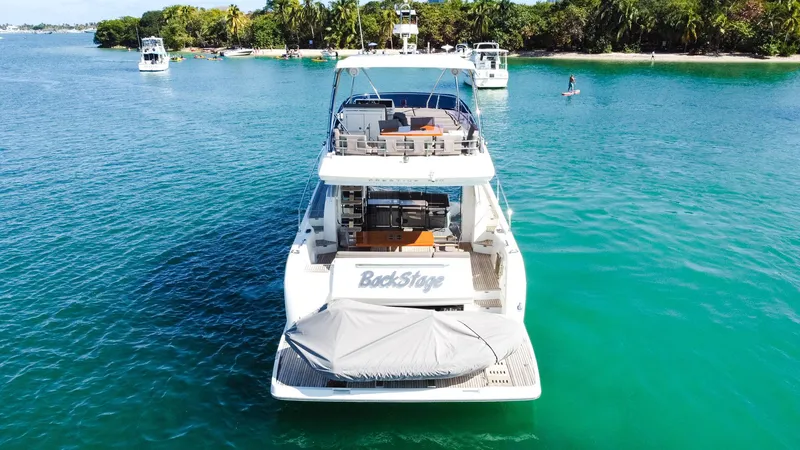 Slide: The Image of 2018 Prestige 560 Flybridge yacht on clear blue water near a tropical island. - 3