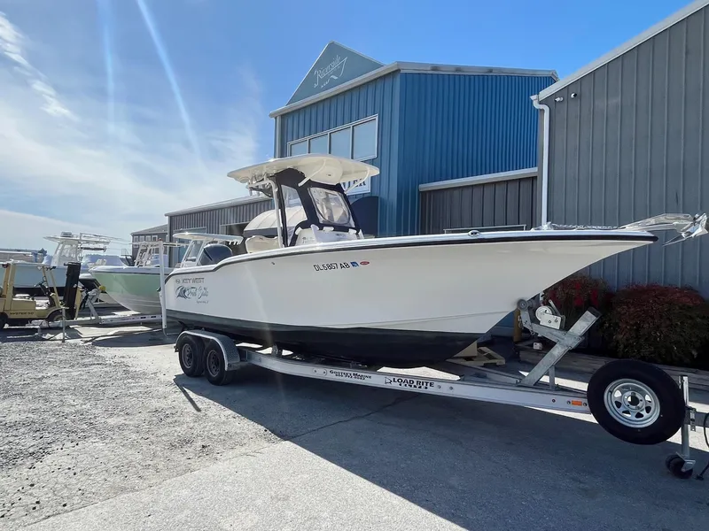 Slide: The Image of 2019 Key West 244 Center Console boat on trailer, parked outside a blue building. - 1