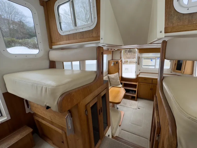 Slide: The Image of Interior of 2006 Nordic Tug 32' Plus, featuring cozy seating and wooden cabinetry. - 12