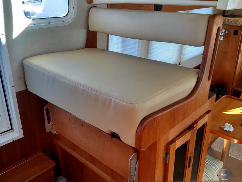 Slide: The Image of Interior seating of a 2006 Nordic Tug 32' Plus, featuring beige upholstery and wooden accents. - 14