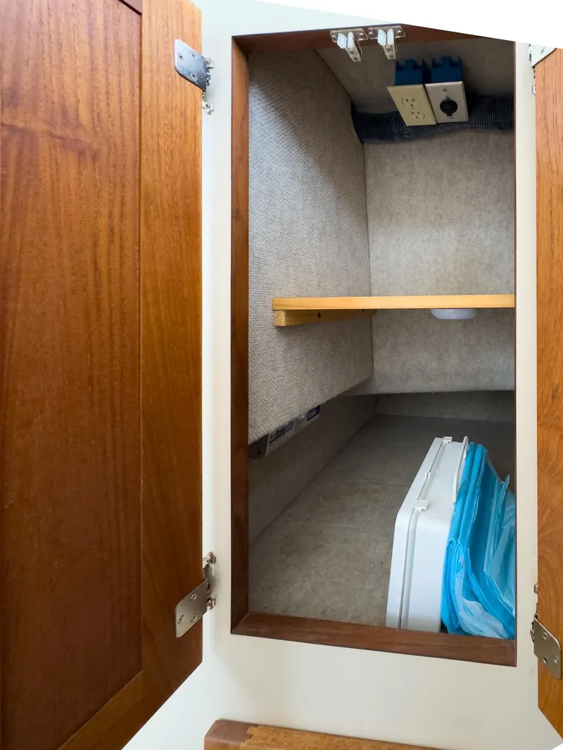 Slide: The Image of Open cabinet interior on 2006 Nordic Tug 32' Plus boat, featuring wooden door and shelf. - 16