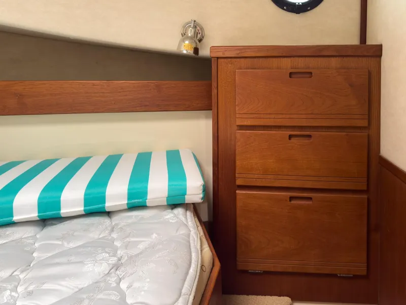 Slide: The Image of Interior of 2006 Nordic Tug 32' Plus with wooden drawers and striped mattress. - 17