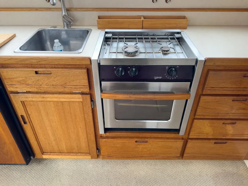 Slide: The Image of 2006 Nordic Tug 32' Plus kitchen with stainless steel stove, sink, and wooden cabinetry. - 5