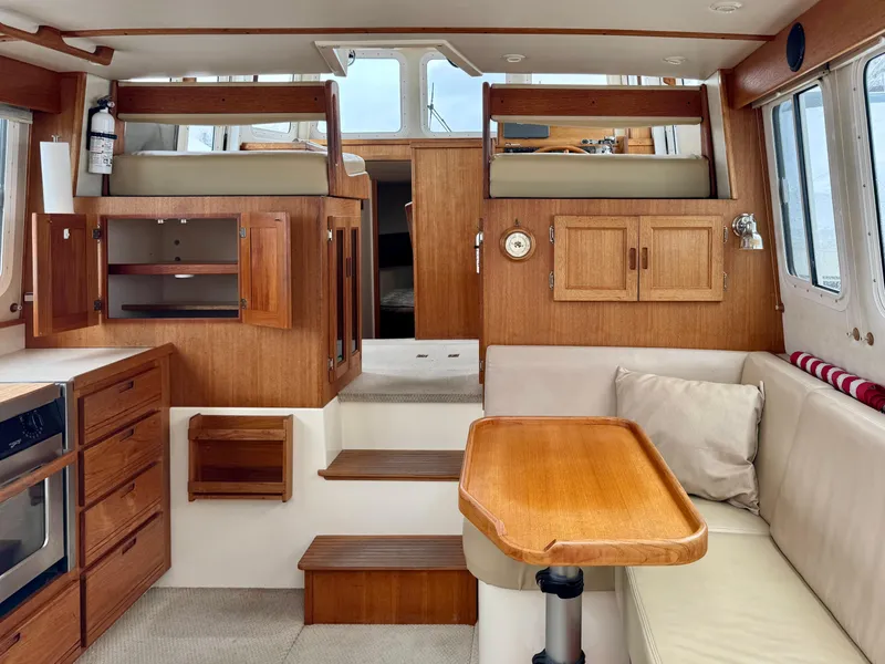 Slide: The Image of 2006 Nordic Tug 32' Plus interior with wood cabinetry, dining area, and cozy seating. - 9