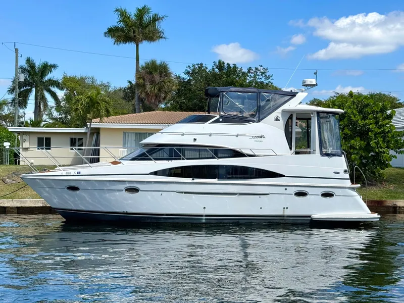 Slide: The Image of 2001 Carver 396 Motor Yacht docked by a waterfront home, under a clear blue sky. - 34