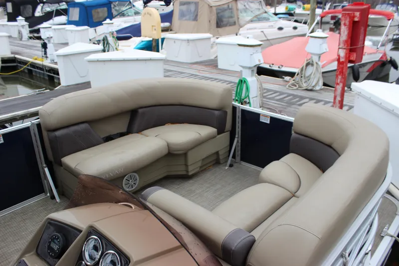 Slide: The Image of 2023 Sylvan Mirage 820 LZ pontoon boat interior with plush seating at a marina. - 17