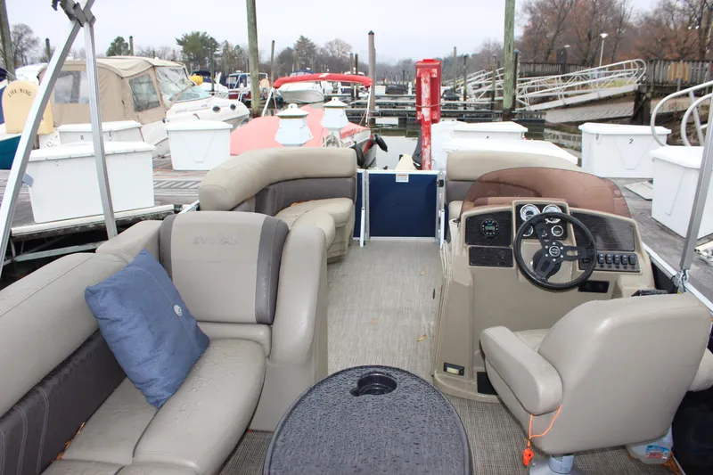 Slide: The Image of 2023 Sylvan Mirage 820 LZ pontoon boat interior at marina, featuring plush seating and steering console. - 20