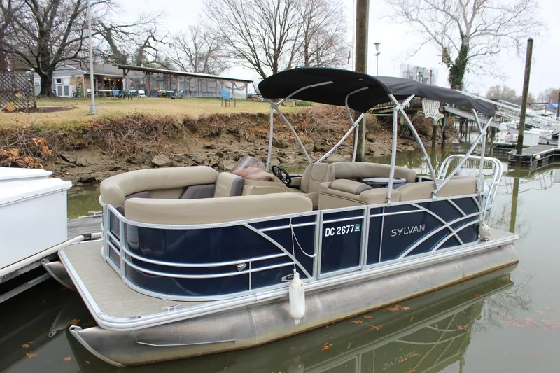 Slide: The Image of 2023 Sylvan Mirage 820 LZ pontoon boat with change room, docked by a riverside. - 7