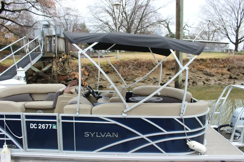Slide: The Image of 2023 Sylvan Mirage 820 LZ pontoon boat with change room, docked by a riverside. - 8