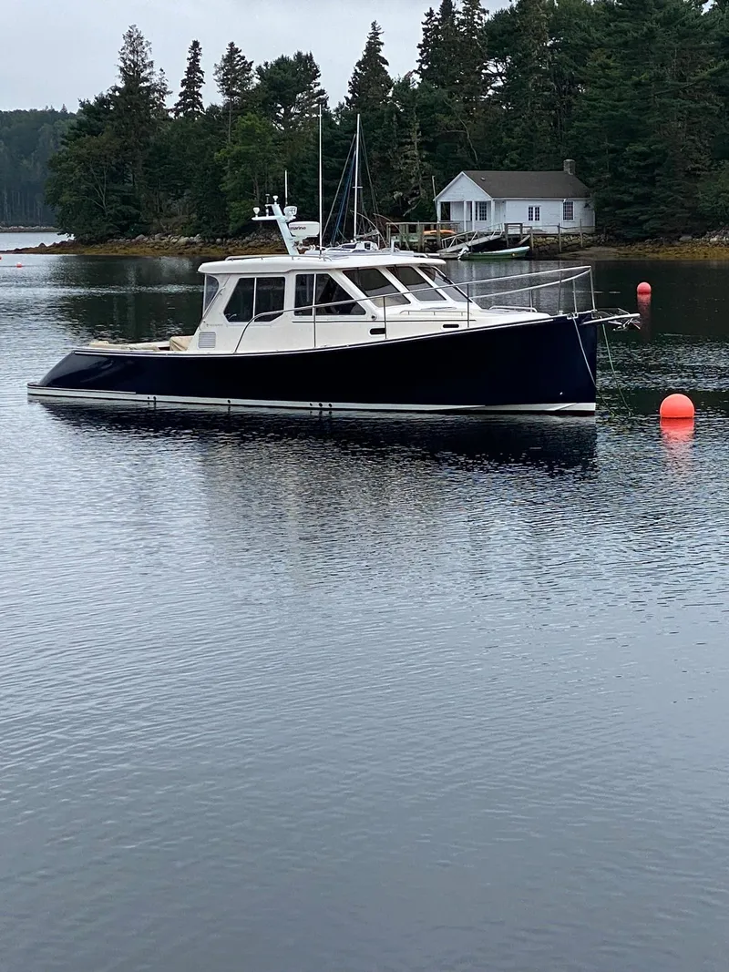 Slide: The Image of 2010 Pearson 38 True North boat on calm water near a forested shoreline. - 29