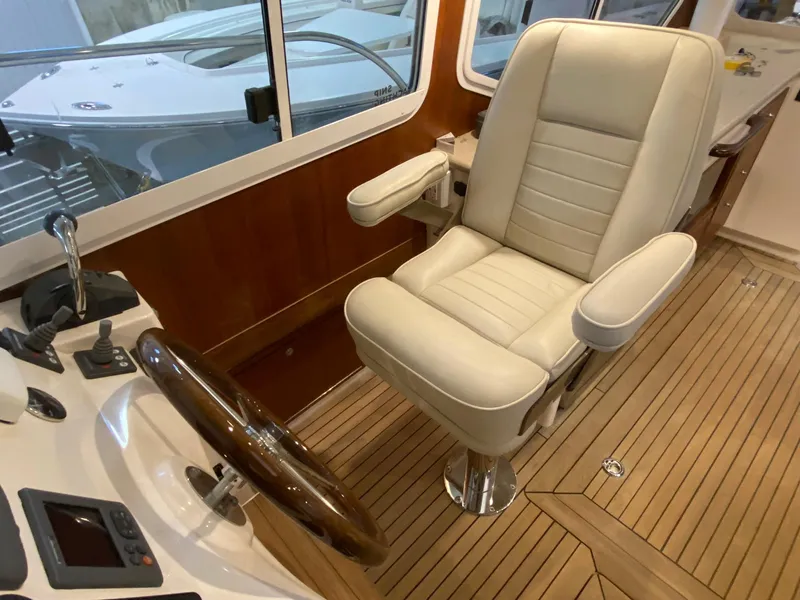 Slide: The Image of Captain's chair in 2010 Pearson 38 True North boat cockpit, featuring wood accents and controls. - 8