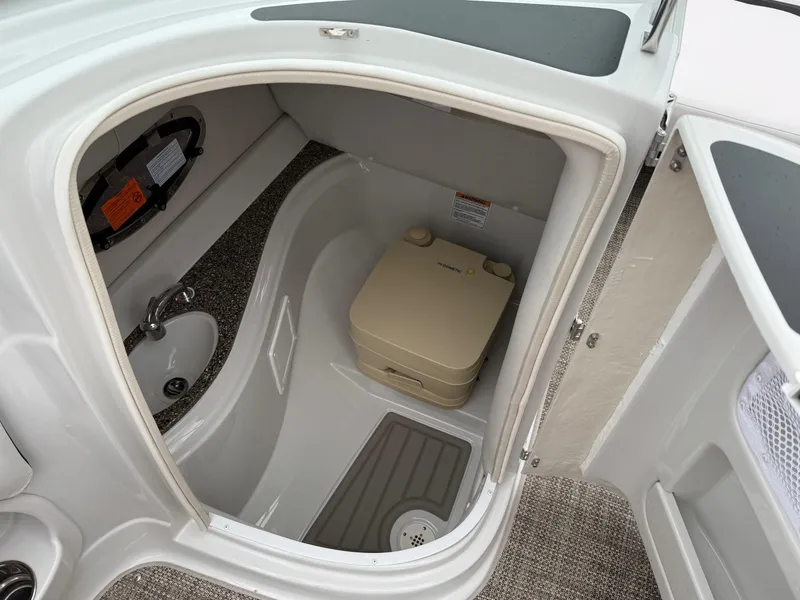 Slide: The Image of 2024 Crownline Eclipse E240 XS boat interior with compact bathroom and portable toilet. - 8