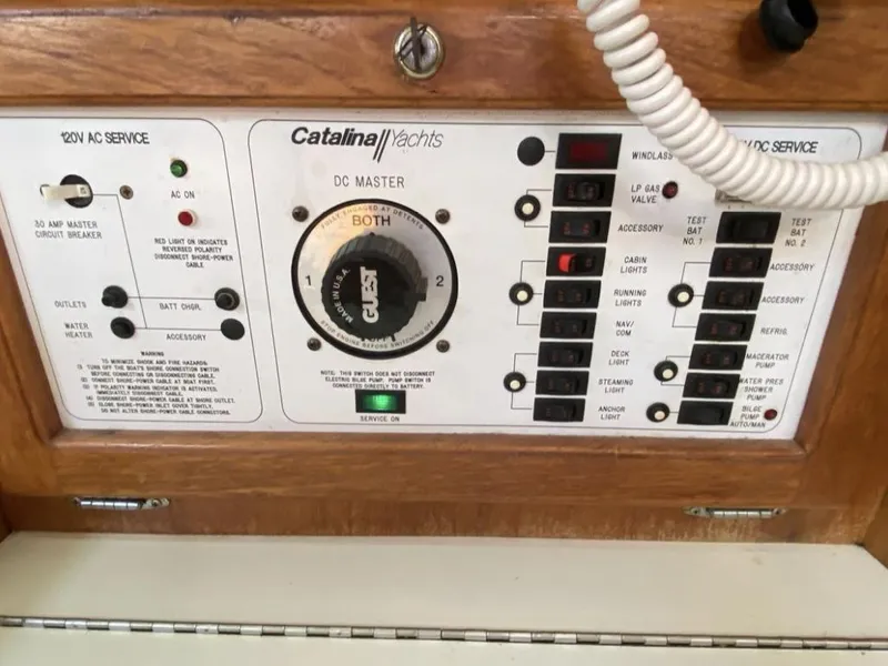 Slide: The Image of Control panel of a 1995 Catalina 36 MkII yacht, featuring AC and DC service switches. - 28
