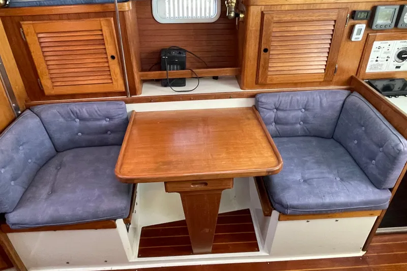 Slide: The Image of Cozy dining area in a 1995 Catalina 36 MkII sailboat with wooden table and cushioned seats. - 39
