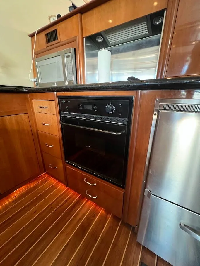 Slide: The Image of 2006 Carver Voyager Sky Lounge kitchen with wood cabinetry, oven, and stainless steel appliances. - 10