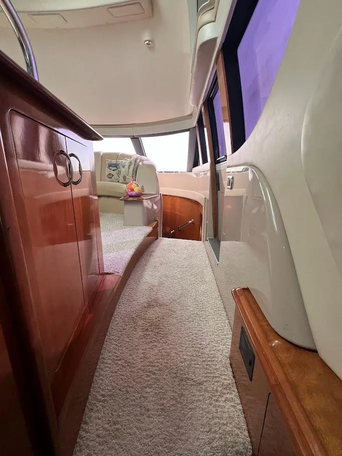 Slide: The Image of Interior of a 2006 Carver Voyager Sky Lounge yacht, featuring elegant wood cabinetry and plush carpeting. - 14