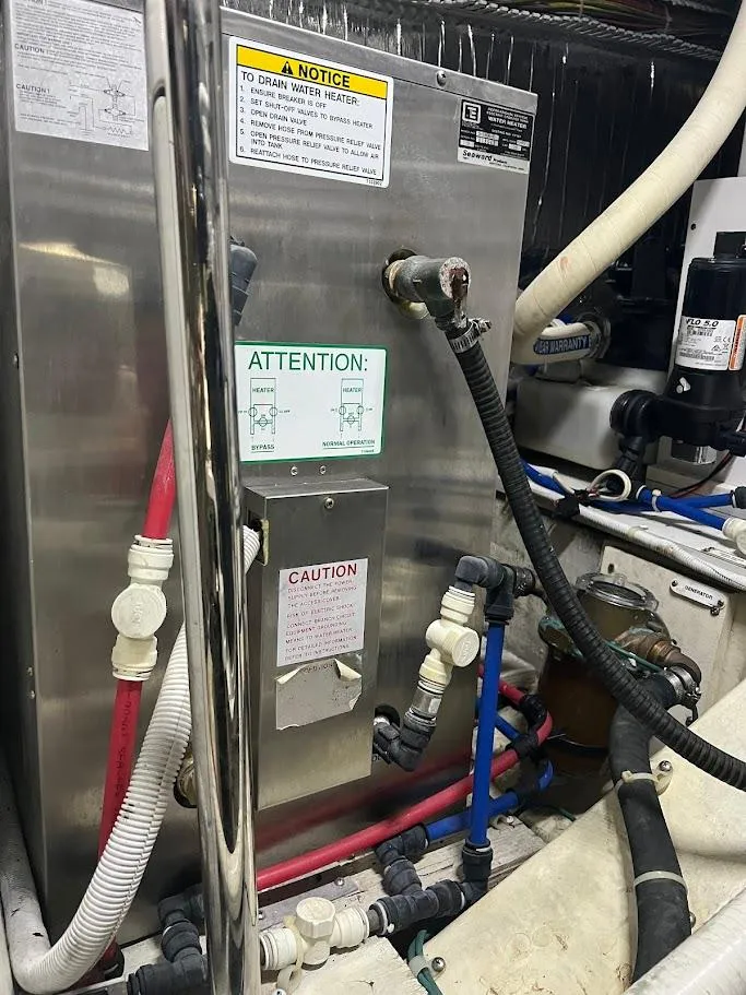 Slide: The Image of Engine room of a 2006 Carver Voyager with various pipes and warning labels. - 48