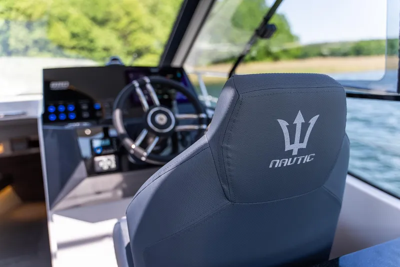 Slide: The Image of Interior of 2025 Nautic 880 boat, featuring steering wheel and branded seat. - 11