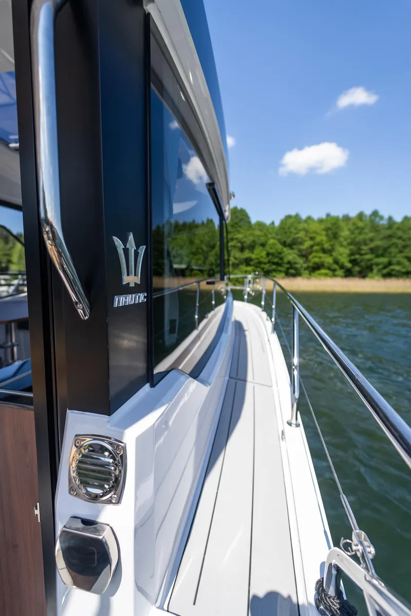 Slide: The Image of 2025 Nautic 880 yacht on water, sleek design, sunny day, lush green shoreline. - 21