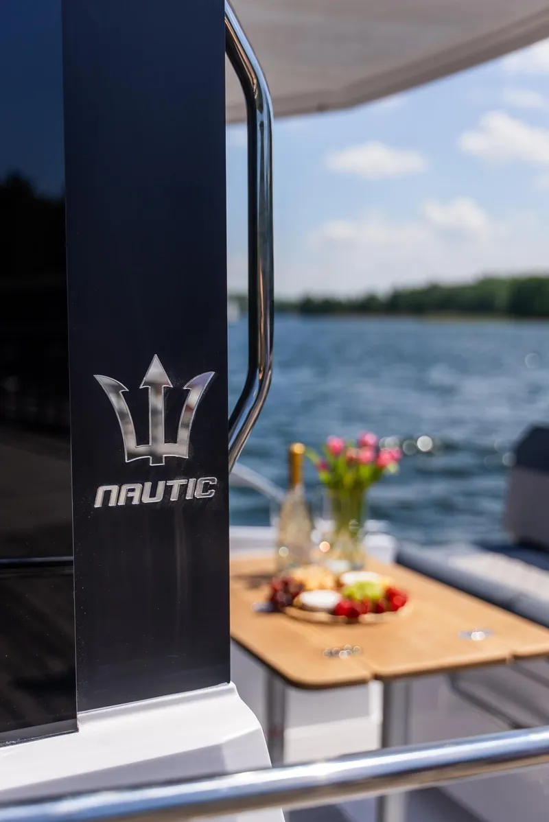 Slide: The Image of 2025 Nautic 880 yacht with elegant deck setup, featuring wine and flowers by the water. - 7