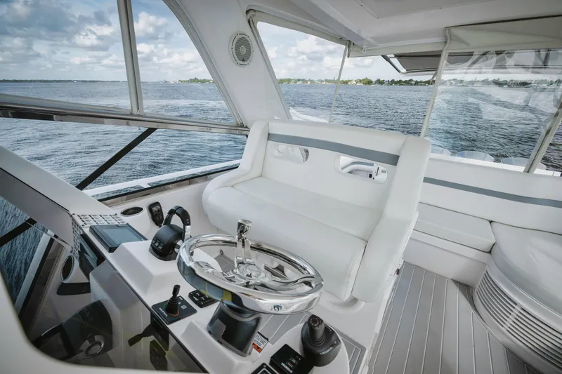 Slide: The Image of 2018 Intrepid 475 Sport Yacht interior with sleek white seating and modern controls. - 22
