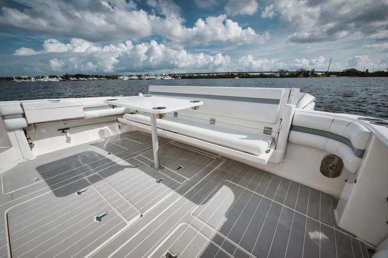 Slide: The Image of 2018 Intrepid 475 Sport Yacht deck with seating, table, and scenic water view. - 30