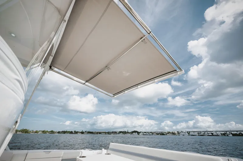 Slide: The Image of 2018 Intrepid 475 Sport Yacht with canopy, overlooking serene waters and cloudy sky. - 31
