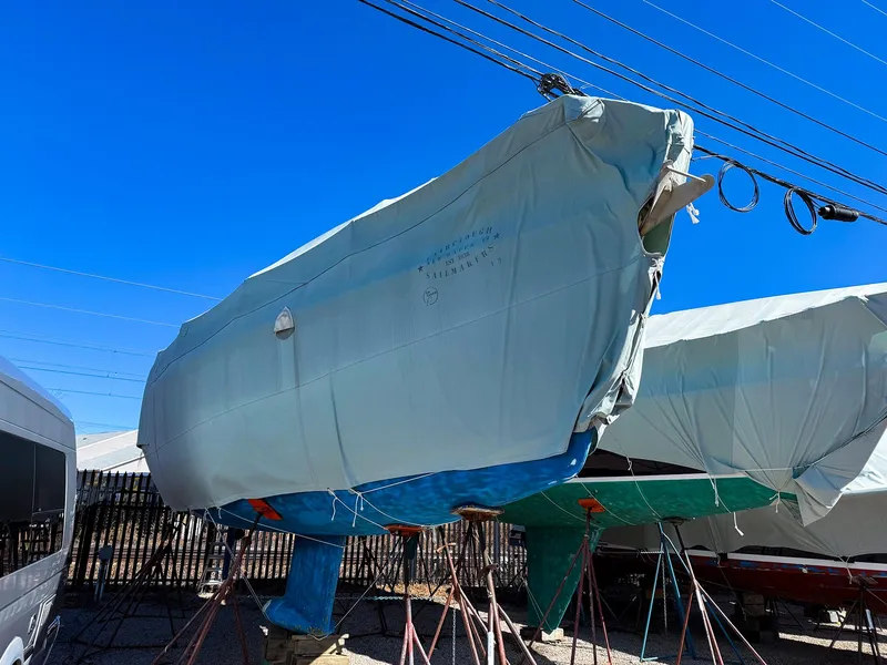 Slide: The Image of Jeanneau 40.3 sailboat, 2005 model, covered and stored outdoors under a clear blue sky. - 11