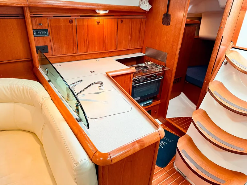 Slide: The Image of Interior of 2005 Jeanneau 40.3 yacht, featuring a compact kitchen and wooden cabinetry. - 17