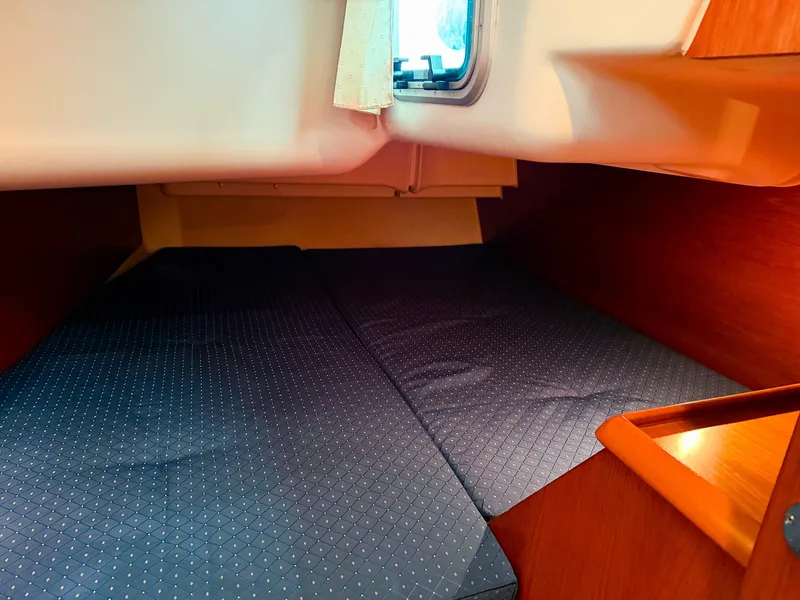Slide: The Image of Interior cabin of 2005 Jeanneau 40.3 sailboat with blue bedding and wooden accents. - 30