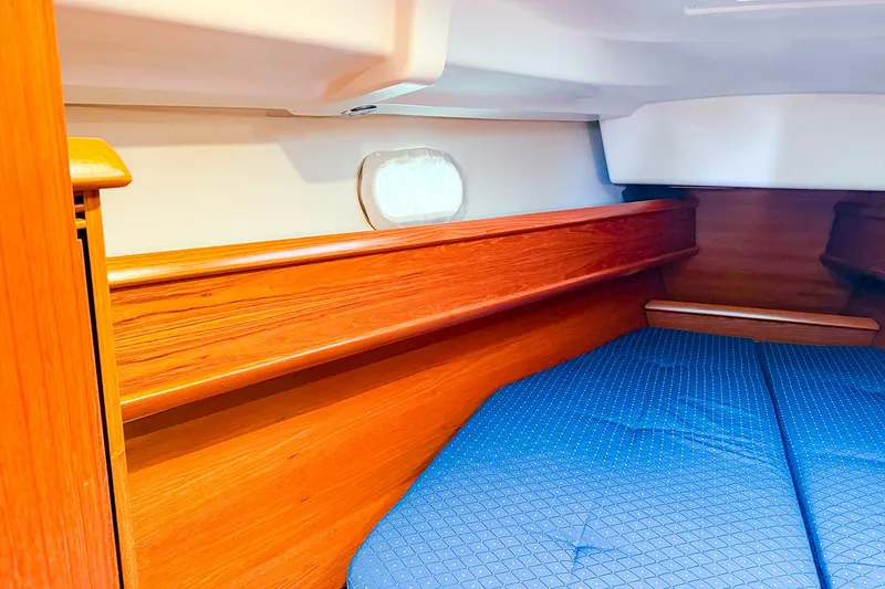 Slide: The Image of Cozy cabin interior of 2005 Jeanneau 40.3 sailboat with wooden finish and blue bedding. - 31