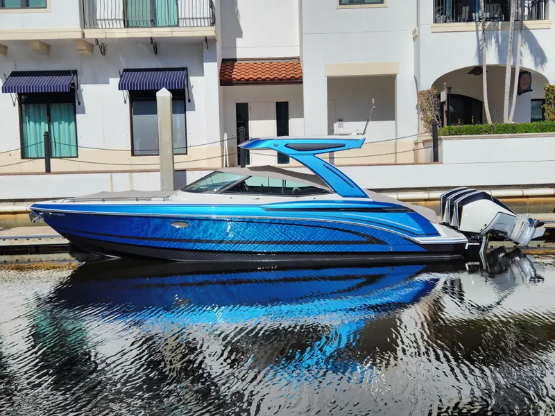 Slide: The Image of 2019 Formula 330 Crossover Bowrider OB in vibrant blue, docked by waterfront buildings. - 0