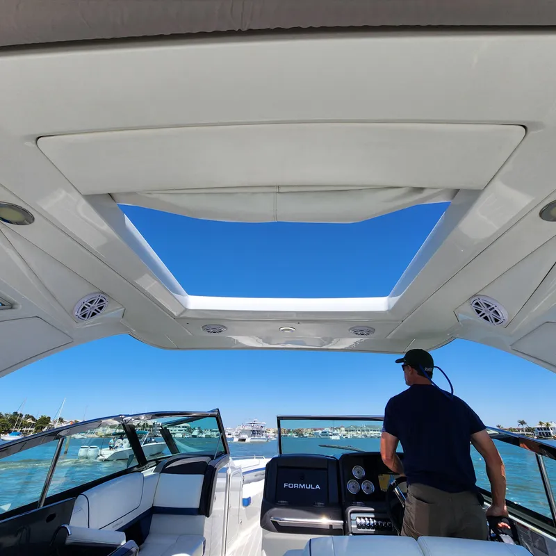 Slide: The Image of 2019 Formula 330 Crossover Bowrider OB, interior view with open sunroof and driver. - 28