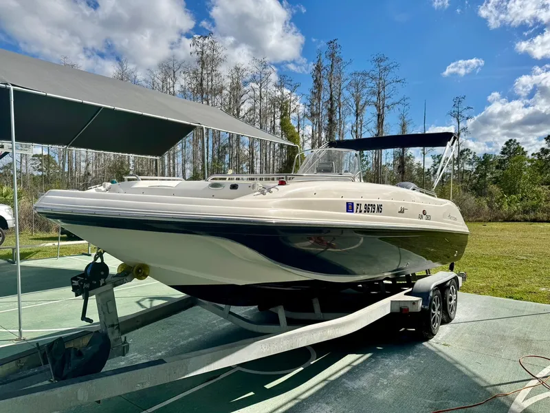 Slide: The Image of 2008 Hurricane FunDeck 211 O/B boat on trailer, under canopy, surrounded by trees. - 5