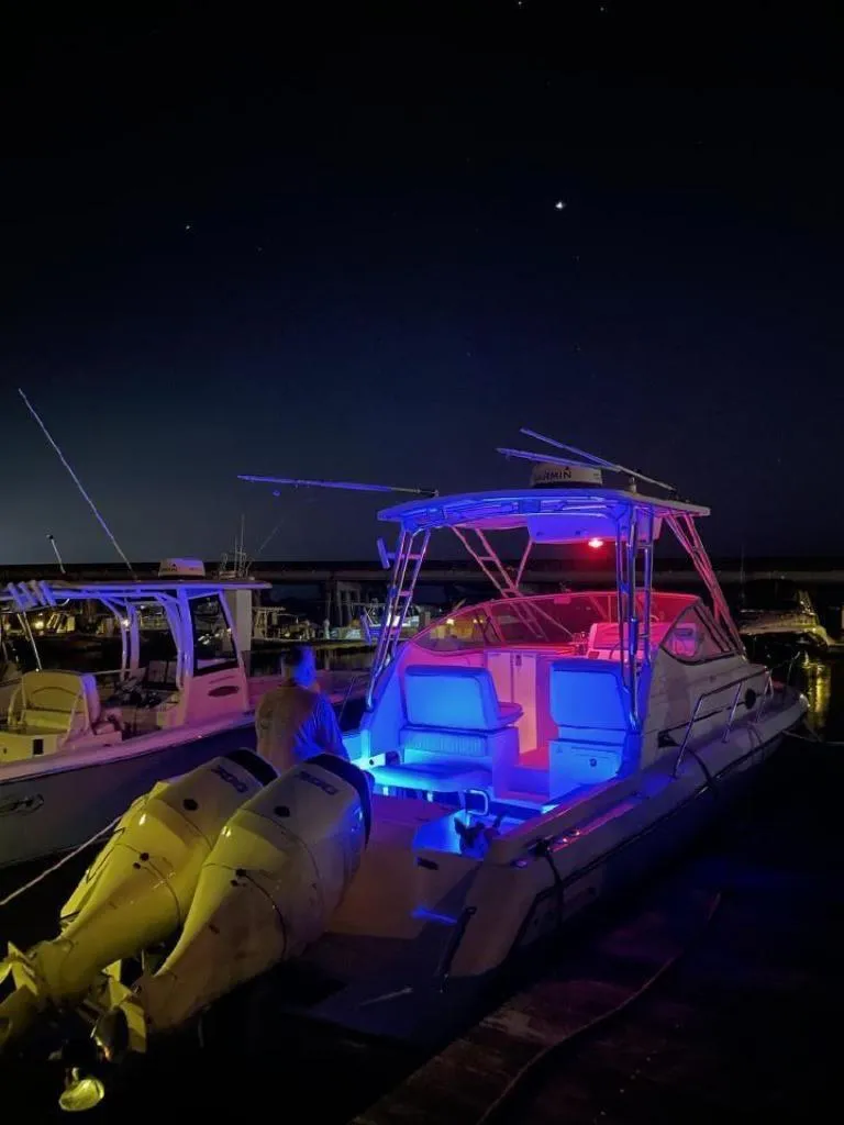 Slide: The Image of 2005 Stamas 290 Express boat illuminated with colorful lights at night in a marina. - 6