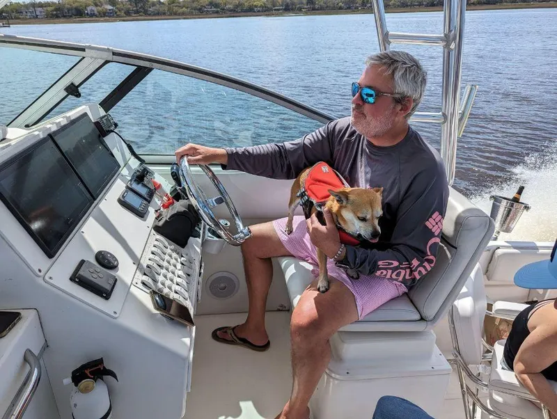 Slide: The Image of Man steering 2005 Stamas 290 Express boat with dog on lap. - 7