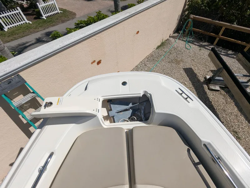 Slide: The Image of 2017 Boston Whaler 240 Dauntless boat with open anchor compartment, docked near a wall. - 17