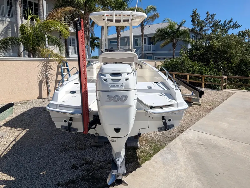Slide: The Image of 2017 Boston Whaler 240 Dauntless boat with outboard motor, parked on gravel near palm trees. - 3
