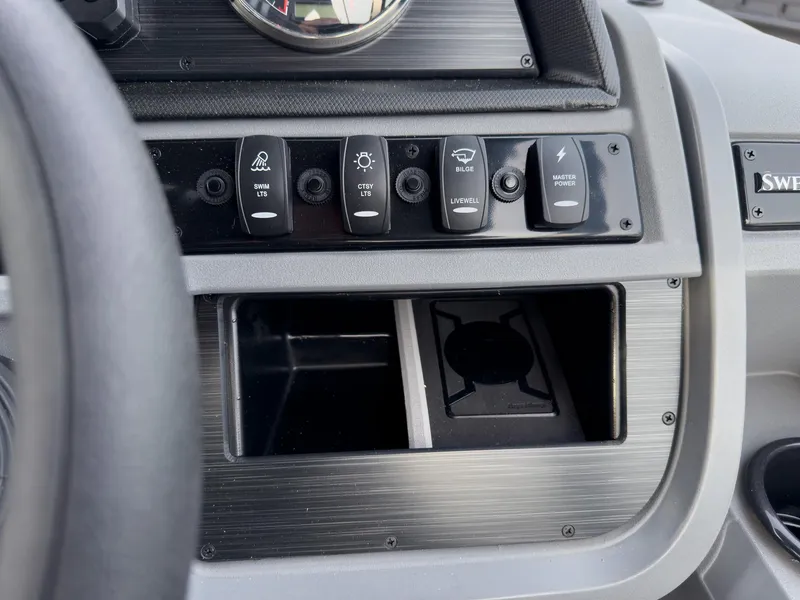 Slide: The Image of Control panel of 2025 Godfrey Sweetwater 22' Split Bench Tritoon, featuring various switches and storage. - 16