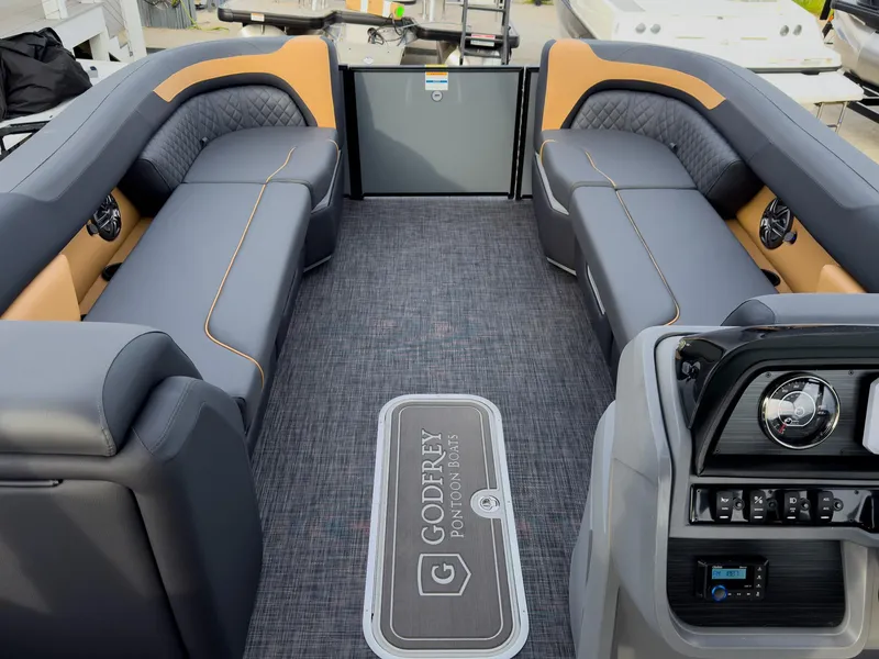 Slide: The Image of 2025 Godfrey Sweetwater 22' Tritoon interior with split bench seating and modern dashboard. - 25