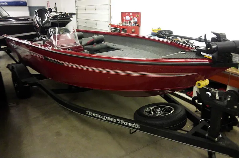 The Image of 2025 Ranger VS1665 SC fishing boat in a garage, red color, on a trailer. - 1