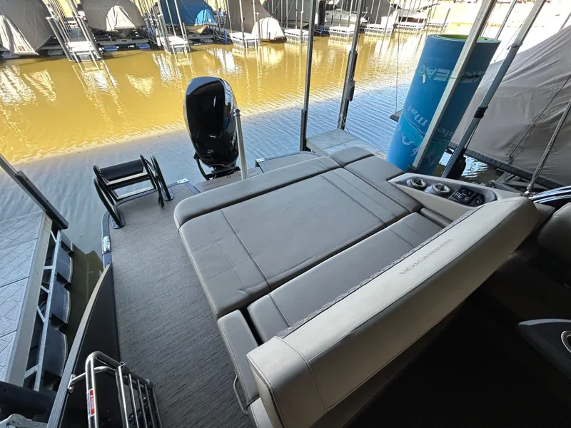 Slide: The Image of 2023 Bennington 25 QSBA boat interior with seating and motor, docked by the water. - 9