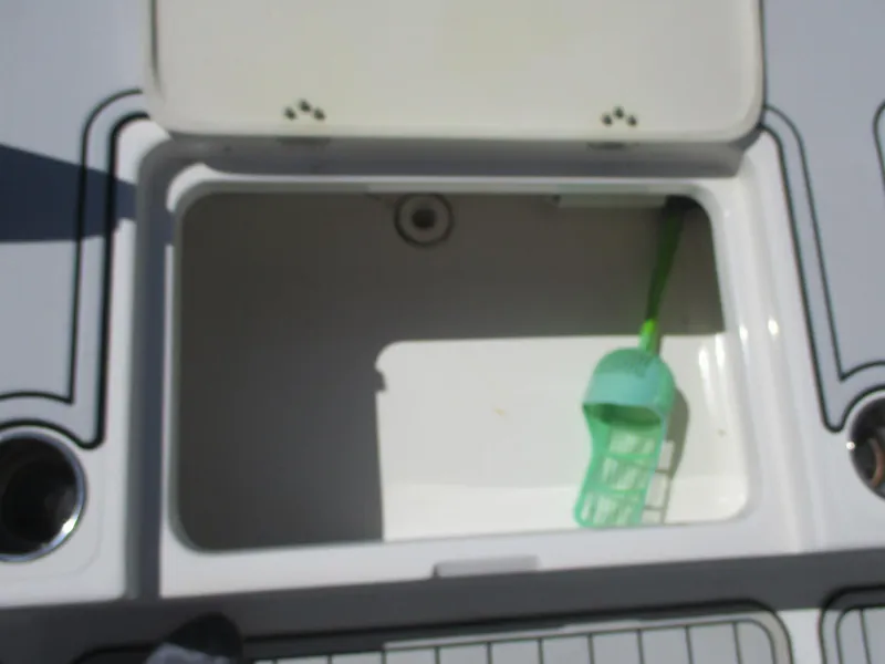Slide: The Image of Open storage compartment on 2018 NauticStar 2400 Sport boat with green scoop inside. - 22